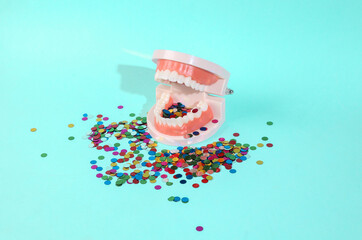 Human jaw model with confetti on a blue mint background. Minimal party concept