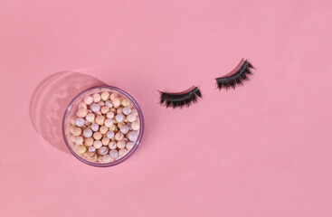 Beauty minimal layout. Balls of powder and false eyelashes on pink background