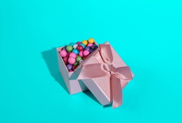 Gift box with colored balls on a turquoise background