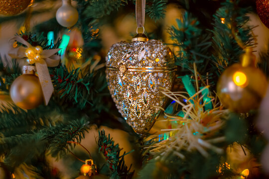 Sparkling heart on a branch of a Christmas tree. Happy New Year, dark postcard. Shallow depth of field. Toned image