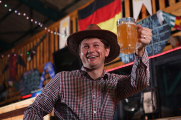 Low angle shot of a cheerful mature cowboy toasting with his beer glass at the bar