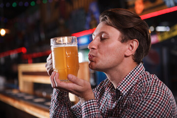 Close up of a man kissing beer mug, relaxing at the pub