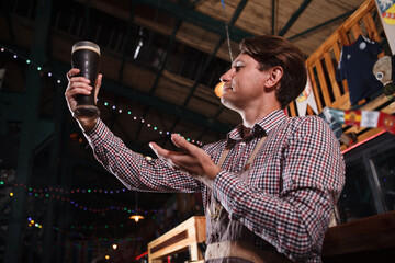 Low angle shot of a professional brewer examining freshly brewed beer at his pub