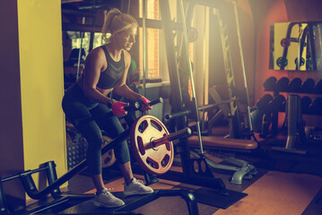 Fit woman work out at the gym training using T-bar rowing back workout