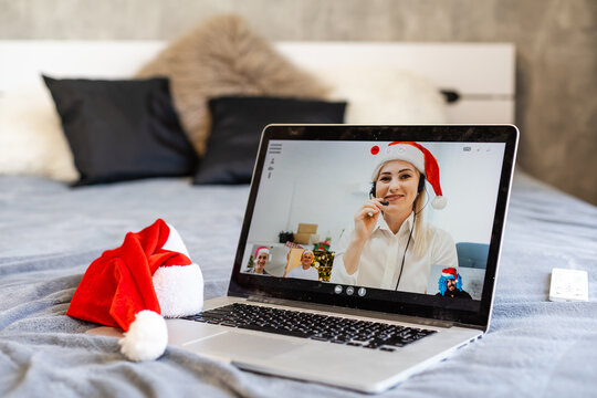 People on virtual call with family and friends exchanging gifts and celebrating virtual christmas online due to social distancing and coronavirus lockdown and quarantines. Image on computer screen.