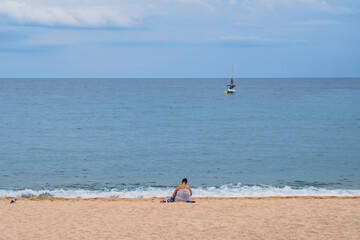 Obese woman sitting alone on the beach, loneliness and solitude concepts