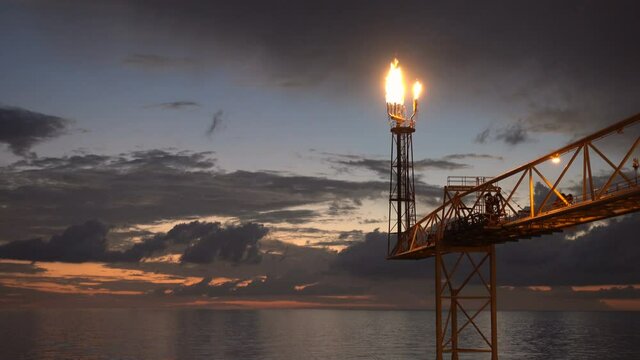 flare burning bridge of oil and gas platform or offshore platform with sun rise and beautiful clouds in the sea for oil and gas industry concept.