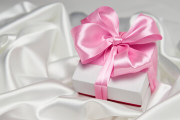 Christmas gift box with ribbon on white silk background