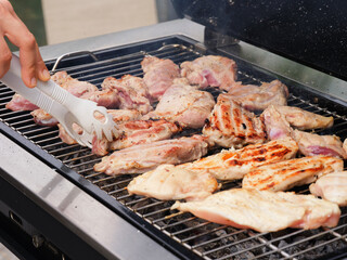 A woman cooking meat on a bbq grill.
