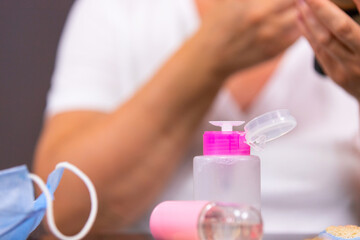 The close up photo of a cosmetic lotion in the pink bottle, spray and medical mask on the table to remove acne after appaired after using the face mask.