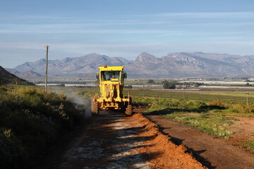 A grader in the process of grading a dirt road