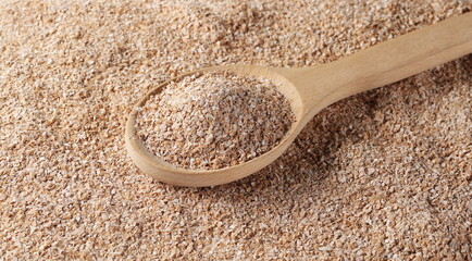 Integral spelt bran in wooden spoon background and texture