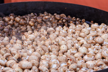 large frying pan with fried mushrooms grilled champignons outdoors street food