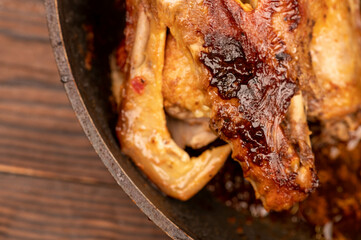 Pieces of roast duck with spices in a frying pan, close-up, selective focus.