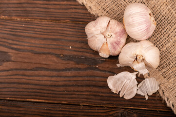Heads of young garlic on a table covered with burlap, close-up, selective focus.
