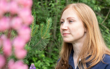 Naklejka premium girl with red hair in the garden with lupins flowers