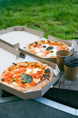 Outdoor lunch with a take away pizza in a cardboard. Vertical photography.