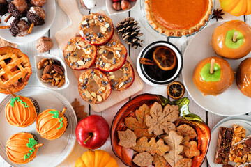 Autumn desserts table scene with various sweet fall treats. Top view over a white wood background.