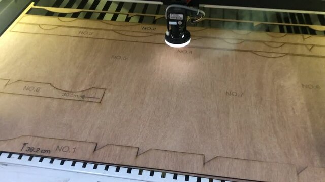 Woodburning. The industrial laser is cutting a pattern on a plywood sheet. Cutting wood parts with a CNC laser cutter. Burning wood cnc machine. The process of creating parts in the CNC machine