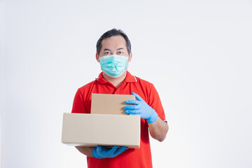 Portrait of Asian delivery man with face medical mask in red cloth holding a box package. Isolated on white studio background with copy space. Delivery,  Sold out online concept.