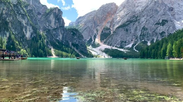 Panoramic shot of Lake Braies (Pragser Wildsee) and mountains and trees of the Dolomites in South Tyrol, Italy during summer with clouds and canoe