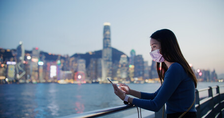 Fototapeta premium Woman wear face mask and use of smart phone at night