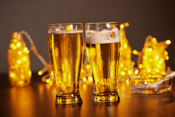 glass of cold beer with foam on the gold light