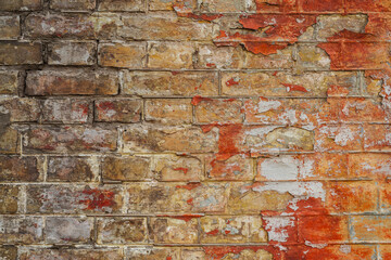 Old brick wall with traces of peeling paint. Aged wall with faded paint. Textured brick wall surface.