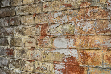 Old brick wall with traces of peeling paint. Aged wall with faded paint. Textured brick wall surface. Angle perspective view.