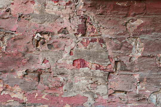 Aged brick wall. Wall covered with faded paint. The wall is covered with several layers of peeling paint.