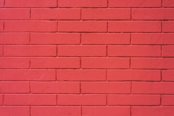 Brick wall painted bright pink. Smooth neat rows of bricks.