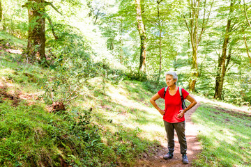 Obraz premium Tired Caucasian senior woman hiking in a forest.