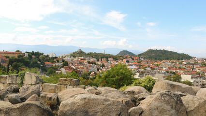 Fototapeta na wymiar panoramic landscape of Plovdiv in Bulgaria with views of the city from the hill of Nevet Tepe - tourist postcard with rocks, buildings, mountains in the background and a blue sky with clouds