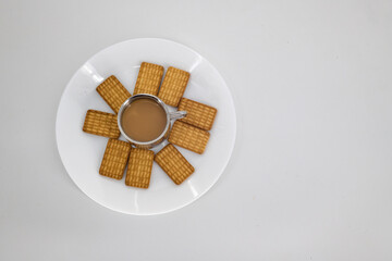 Indian tea on a sliver cup and Wheat biscuits in the white plate with white background. Indian biscuits popularly known as Chai-biscuit in India.