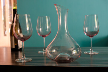 An empty wine carafe and three glasses in the interior sunny cuisine. Remains of red wine on the glass. Wine tasting. 