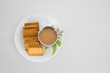 Indian tea on a sliver cup and Wheat biscuits in the white plate with white background. Indian biscuits popularly known as Chai-biscuit in India