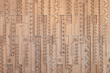 Milled and cut stone pine wooden wall with different patterns and symbols