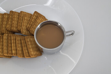 Indian tea on a sliver cup and Wheat biscuits in the white plate with white background. Indian...