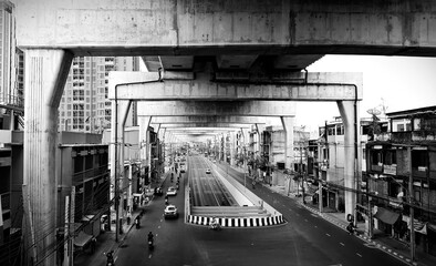 Landscape view of road and vehicles under the sky train structure in black and white