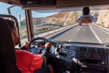 Truck driver, seen from inside the cab, driving on the highway and at the entrance of a tunnel.