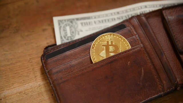 Closeup of a golden bitcoin medal in a leather purse. Crypto wallet with golden bitcoin.