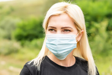 Closeup photo of young beautiful woman in reusable virus protective mask on face against coronavirus.