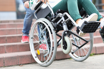 Fototapeta na wymiar Man pulling disabled woman in wheelchair up steps closeup