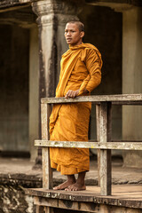 Fototapeta premium Young Buddhist monk standing by railing in temple, Angkor Wat, Siem Reap, Cambodia