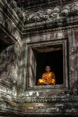 Fototapeta premium Young Buddhist monk meditating in temple in Angkor Wat, Siem Reap, Cambodia
