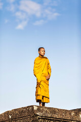 Naklejka premium Young Buddhist monk standing outside temple in Angkor Wat, Siem Reap, Cambodia