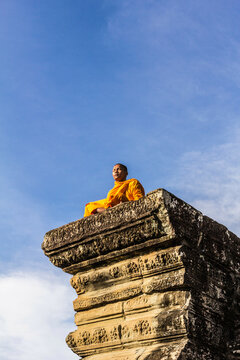 Young Buddhist monk sitting outside temple in Angkor Wat, Siem Reap, Cambodia