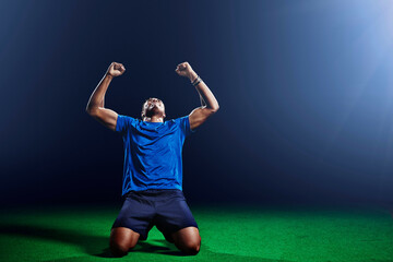 Male soccer player kneeling with arms raised © Image Source Limited