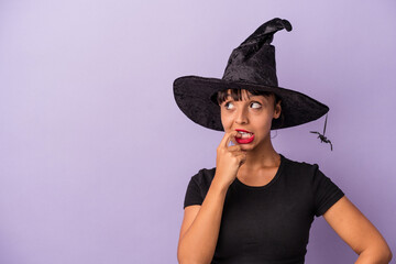 Young mixed race woman disguised as a witch isolated on purple background  relaxed thinking about...