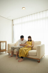 Man touching pregnant woman's stomach on sofa